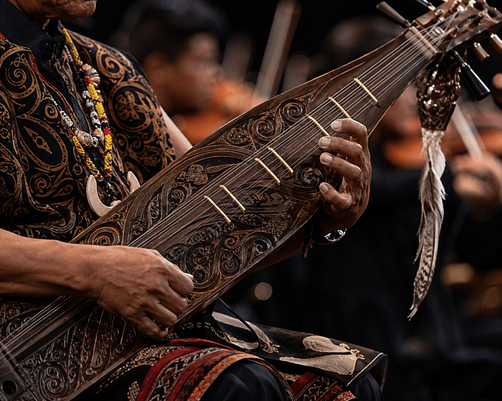 Permainan instrumen tradisional Sape Dayak berpadu dengan orkestra modern dalam pementasan musik budaya.